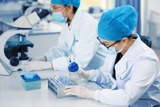 Two scientists wearing masks working in a laboratory.