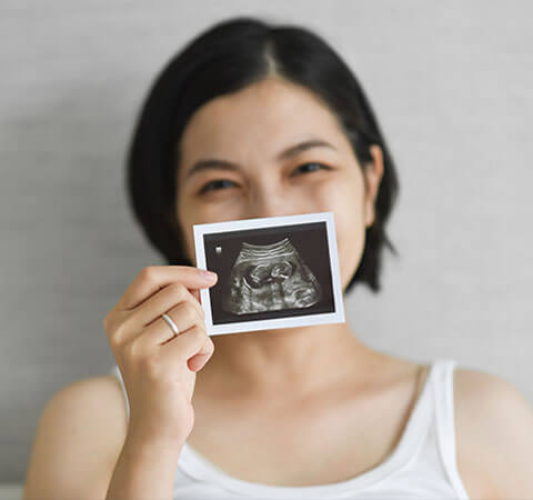 woman holds ultrasound and smiles