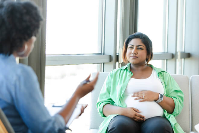 A pregnant woman listens intently during a consultation