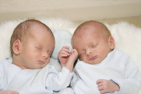 Twin babies sleeping next to each other.