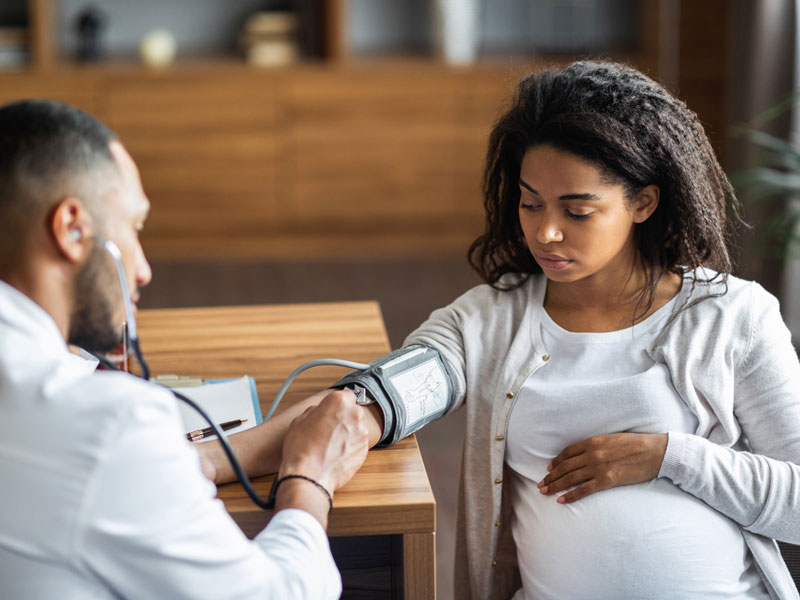 A young woman gets blood pressure checked by doctor at appointment