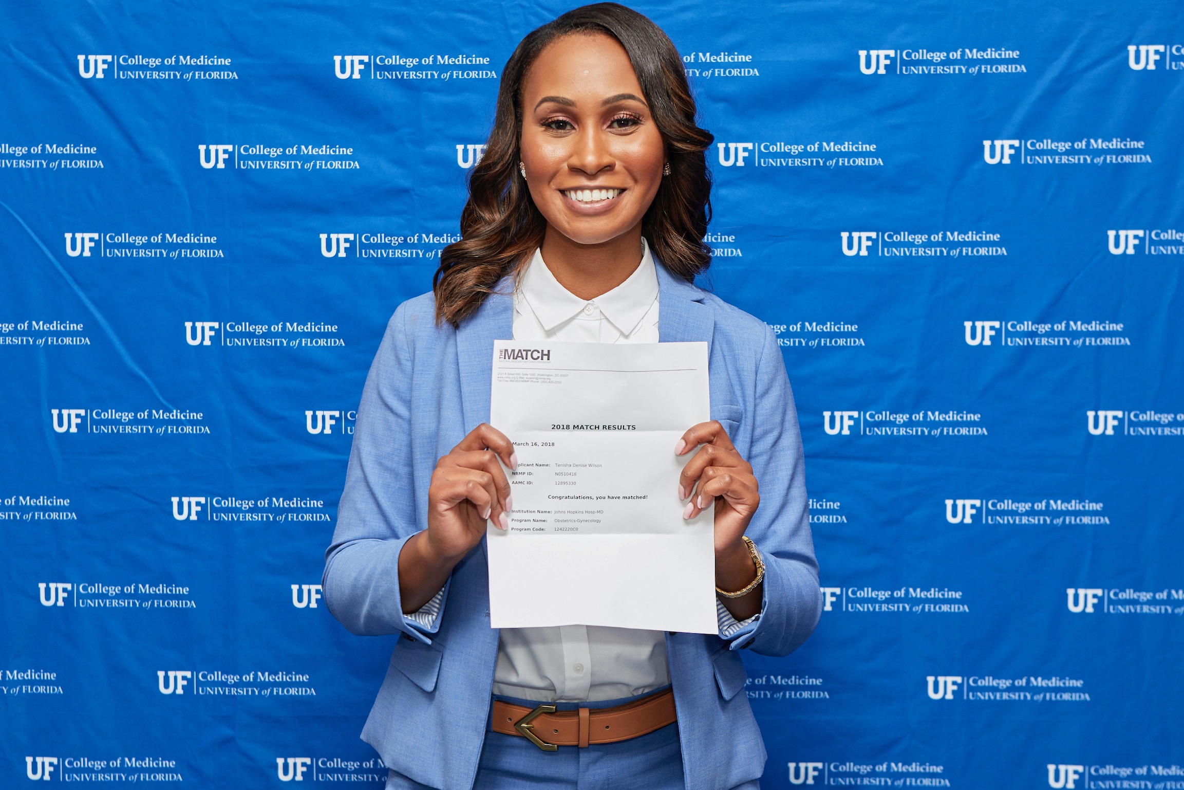 woman holds acceptance letter in front of Johns Hopkins background