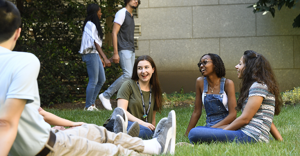 a group of students sit in the grass on campus