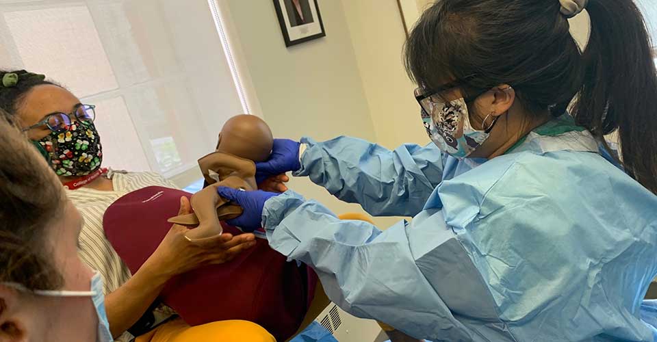 Two residents work together to simulate a vaginal delivery