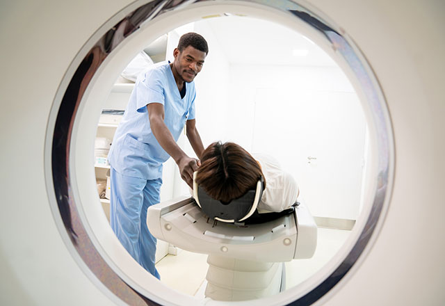 a tech helps a woman into a CT machine