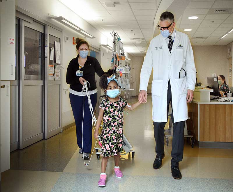 Dr. Klugman, a nurse and a child walk down the hallway