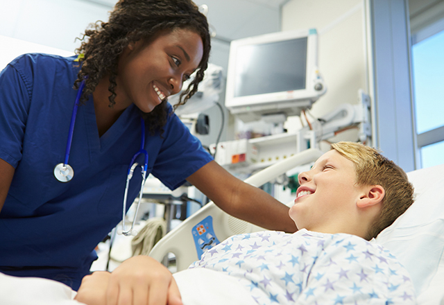 nurse laughing with boy in hospital bed - heart and vascular institute