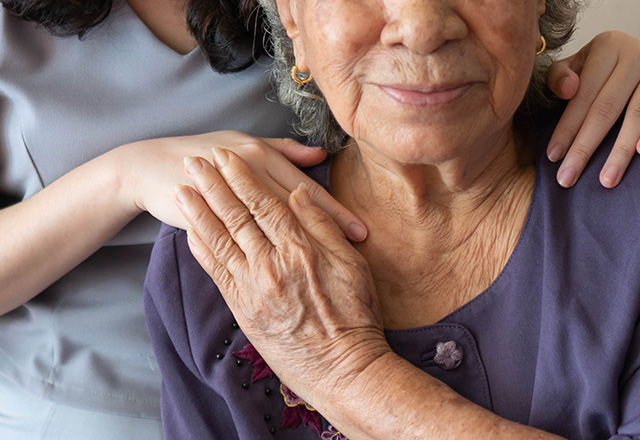 Friendly relationship between caregiver and happy elderly woman during nursing at home.