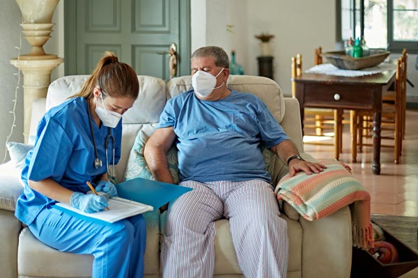 Physician sitting on couch with patient in home