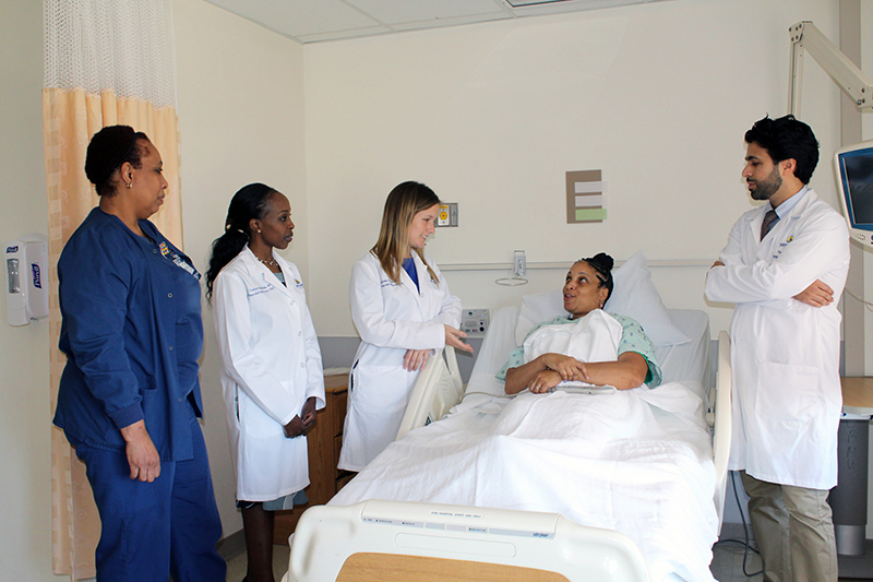 Hospitalists visiting with a patient in hospital bed