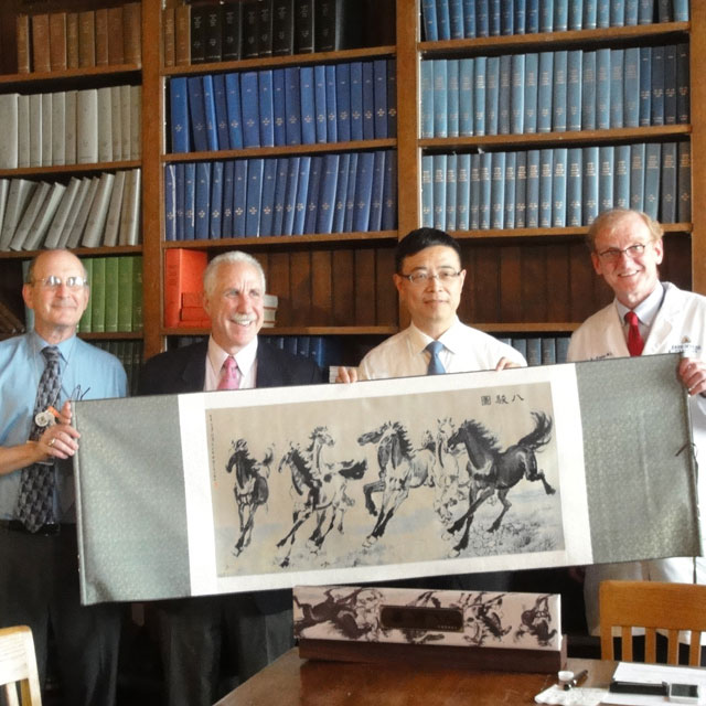Group of directors and Johns Hopkins staff holding a piece of original artowrk