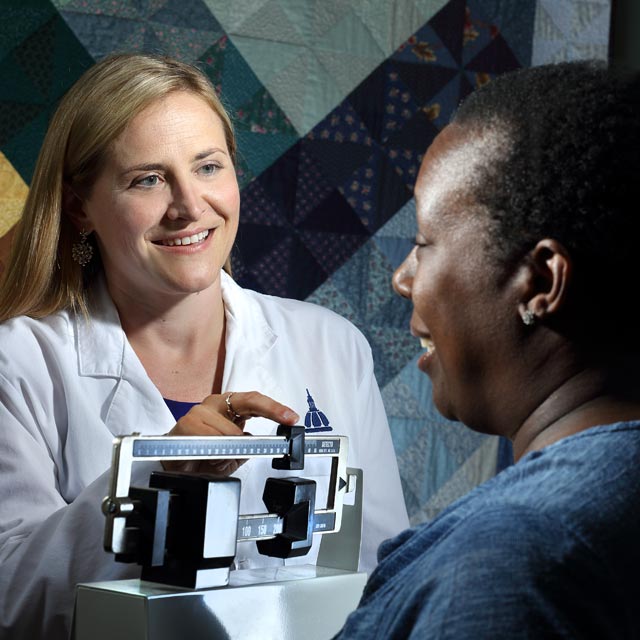 The photo shows Kimberly Gudzune speaking with a patient.
