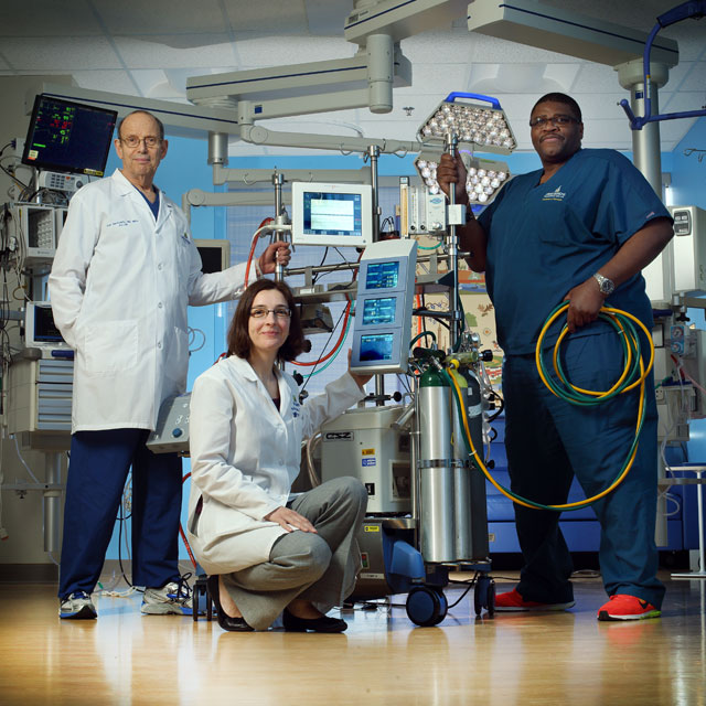 Three doctors standing in front of medical equipment