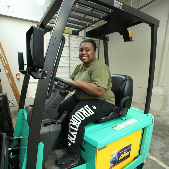 The photo shows Jessica Waters on a forklift. 