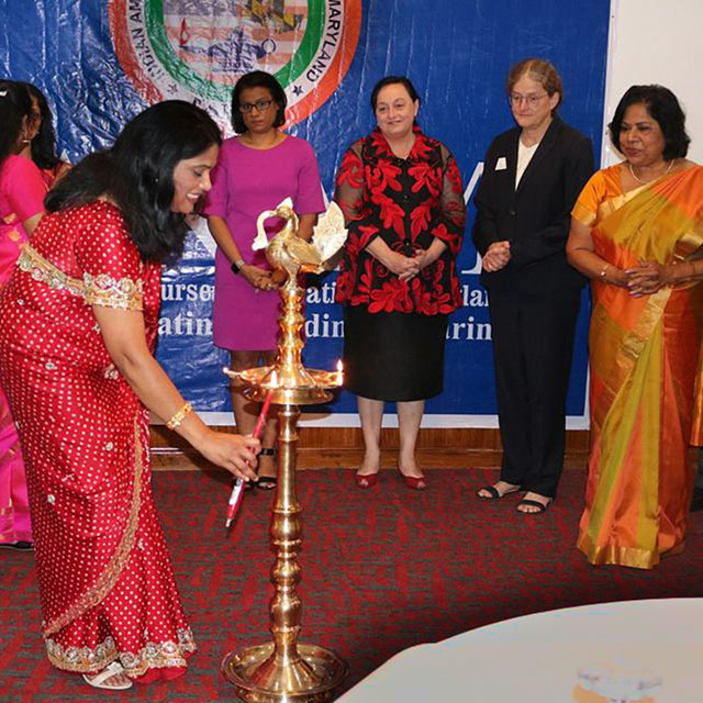 The photo shows Alphie Rahman lighting a lamp.