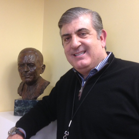 Nicholas Theodore, head of the Neurological Spine Center in the Johns Hopkins Department of Neurosurgery, stands beside a bust of Walter Dandy.