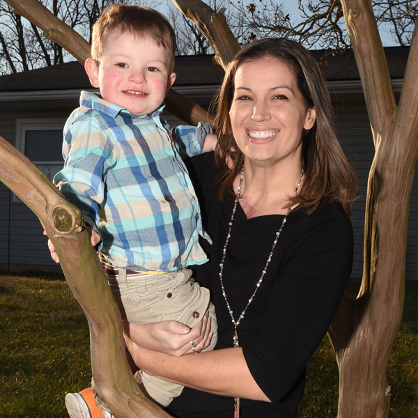 Caroline Zeman standing, smiling and holding her young son