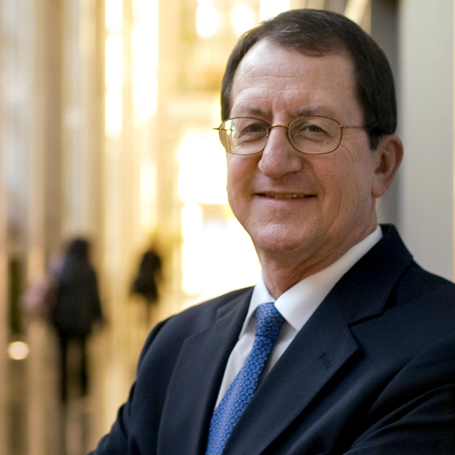 photo of Ronald R. Peterson wearing a blue suit and tie, arms folded. 