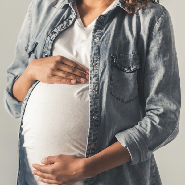 Young pregnant woman resting her hands on her stomach