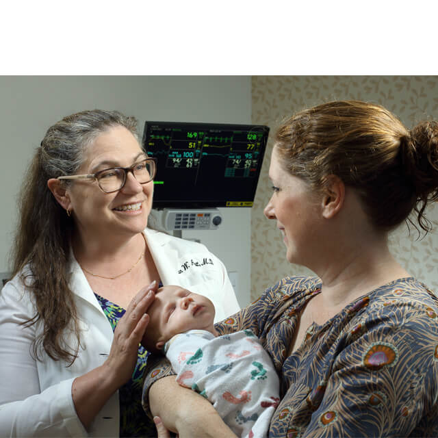 Neonatologist Susan Aucott with a young patient and mom.