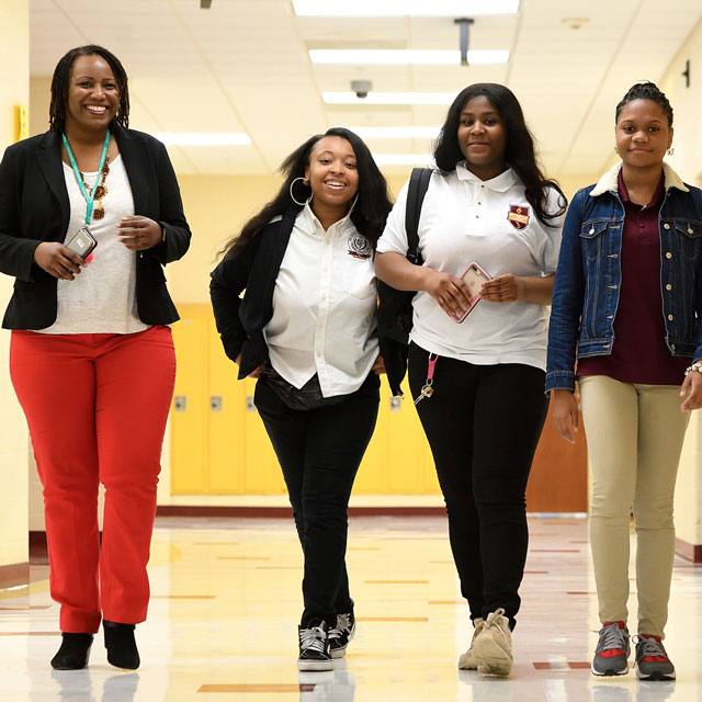 Photo shows Alexia Smith of the Johns Hopkins University Office of Community Affairs, with Dunbar High School students Caitlun Clark, Nayonna Earl and Simone Wade.