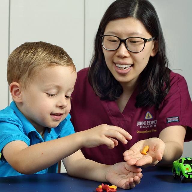 A photo shows occupational therapist Yun Kim helping a patient improve fine motor skills.