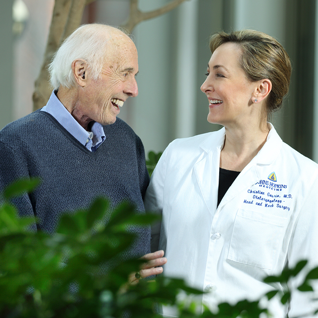 Photograph of patient Al Friendly Jr. smiling a laughing with Dr. Christine Gourin. They are looking at each other joyfully. 
