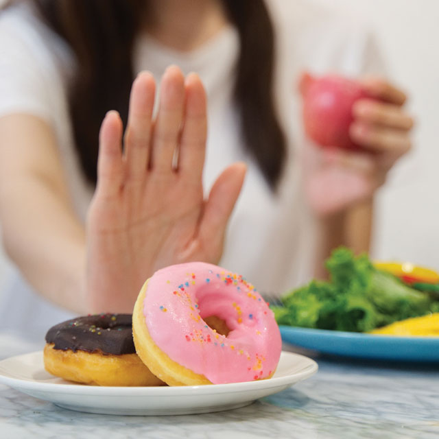 photo of two hands, one pushing away a donut and the other choosing a salad.
