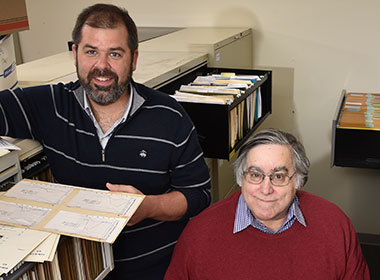 Photo shows researcher Alden Gross and study director Joseph Gallo looking through file cabinets of archive material. 