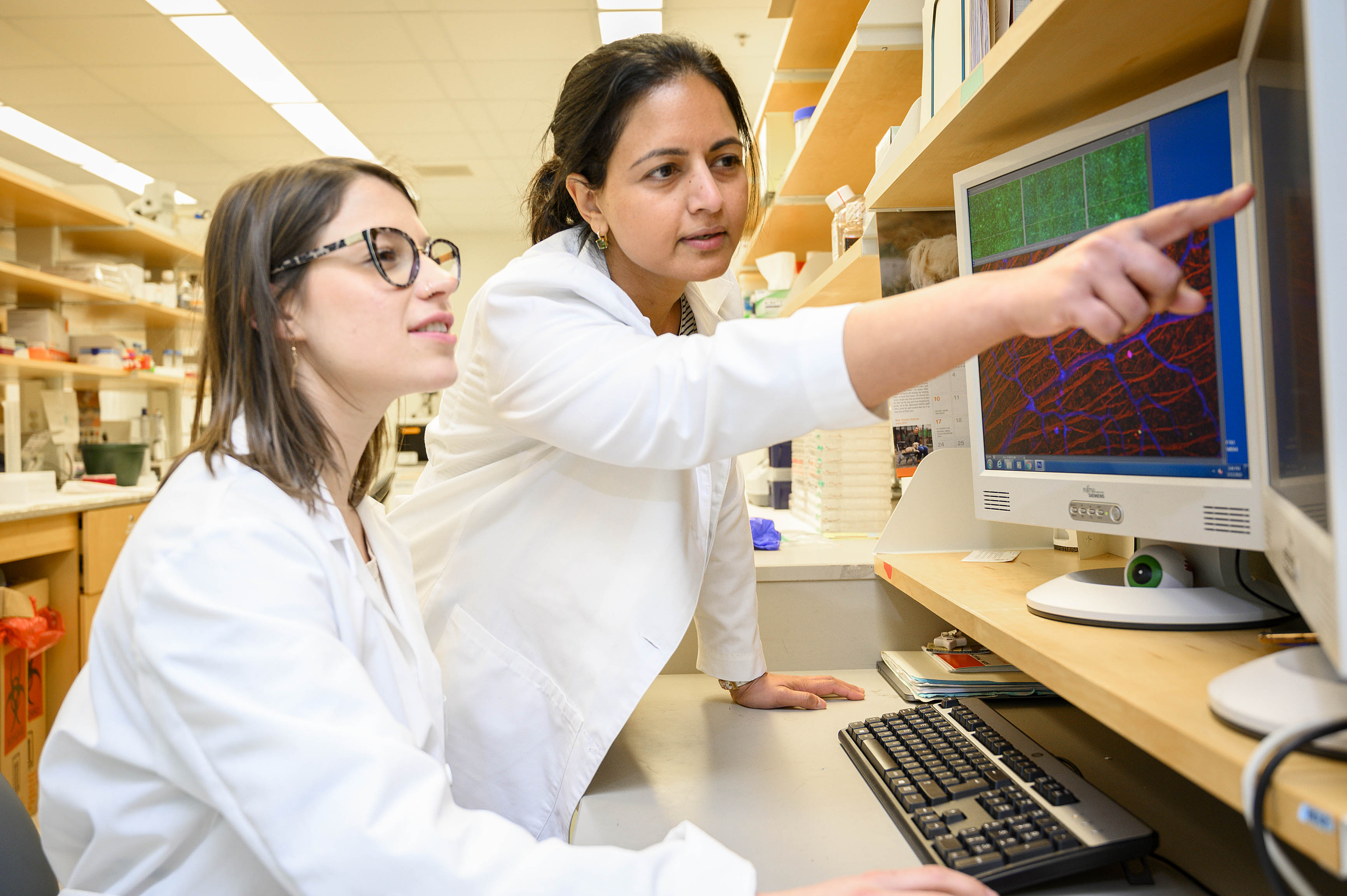 Dr. Mira Sachdeva and technician Kelcy Klein observing lab findings on a computer screen