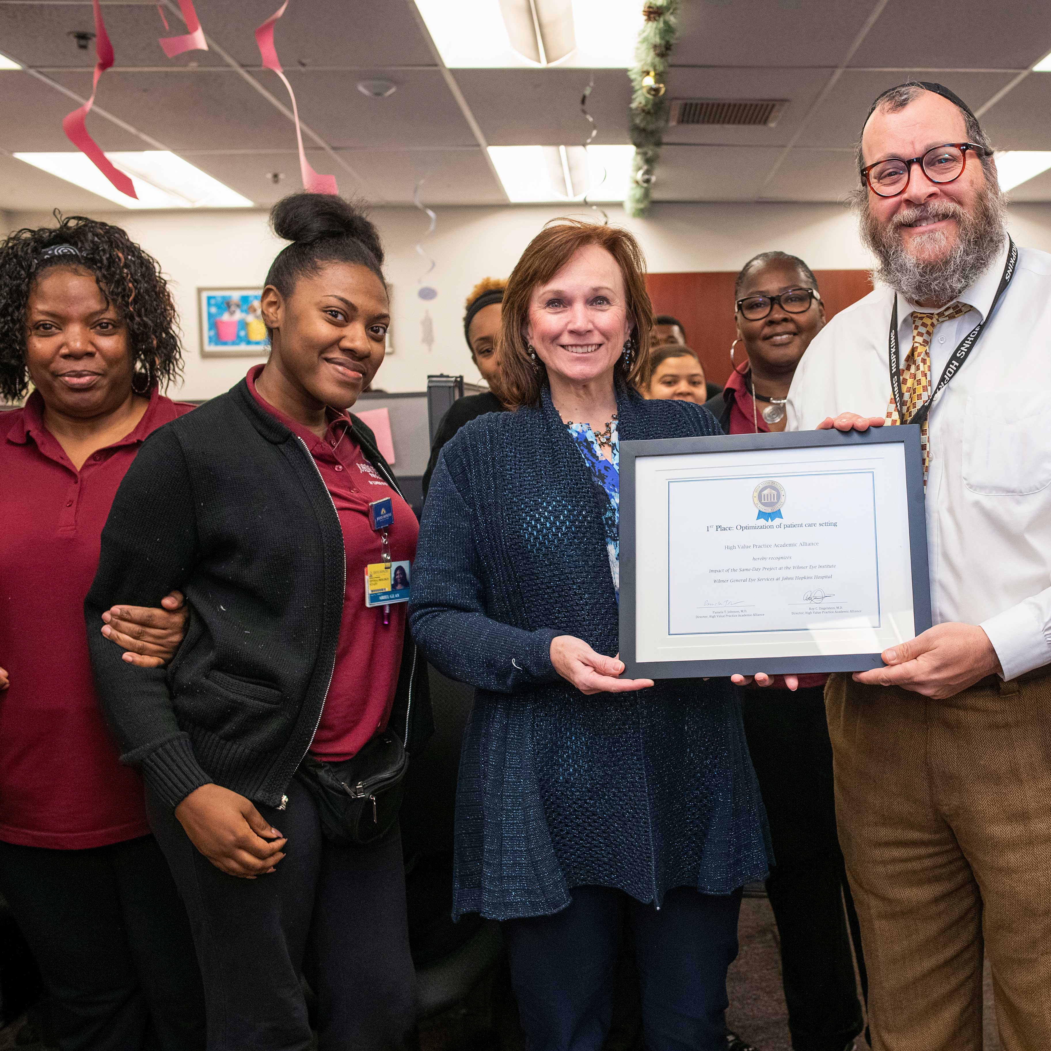 Dr. Eric Singman and members of the Wilmer Eye Institute call center team holding an award
