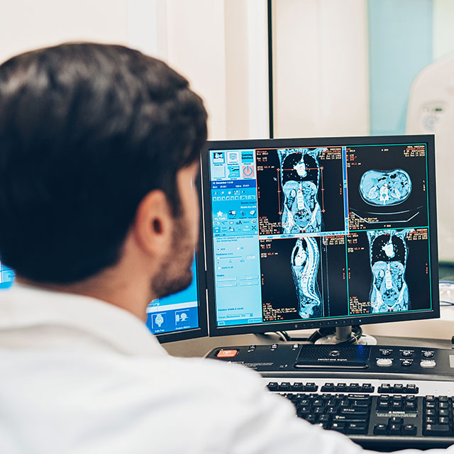 Doctor sitting at computer while patient is in MRI Machine 