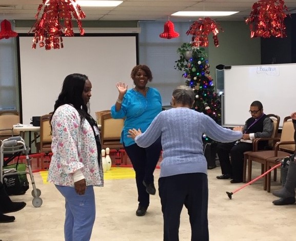 A photo shows a recreation therapist dancing with a Hopkins ElderPlus client. 