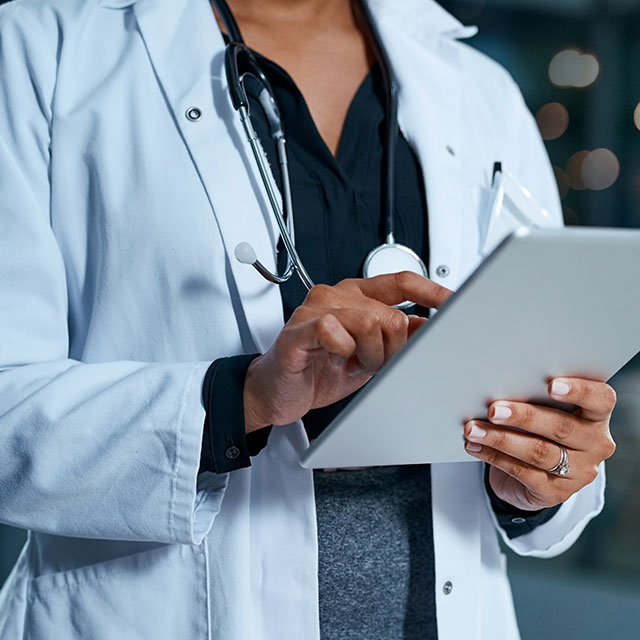 Doctor stands with tablet.