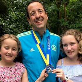 Photo shows Rodney Vieira hugging his two daughters after running the Boston marathon