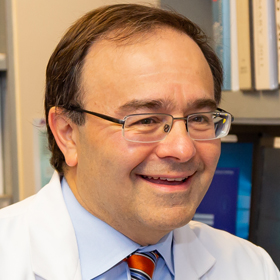Photo of Gregory Kumkumian, medical director of the cardiac catheterization laboratory and cardiac rehabilitation program at Suburban Hospital, seated at his office desk.