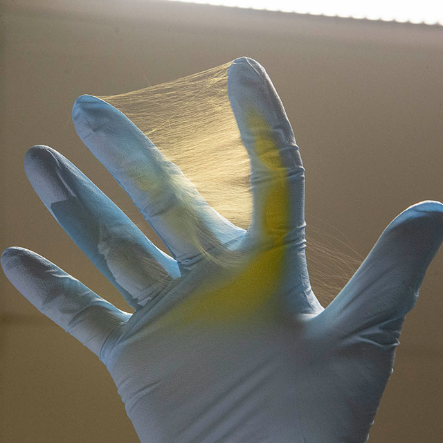 A clinician holds electrospun fibers that consist of porous electrospun polycaprolocatone (PCL) host polymer and anti-cancer drug acriflavine, which gives it the yellow color.
