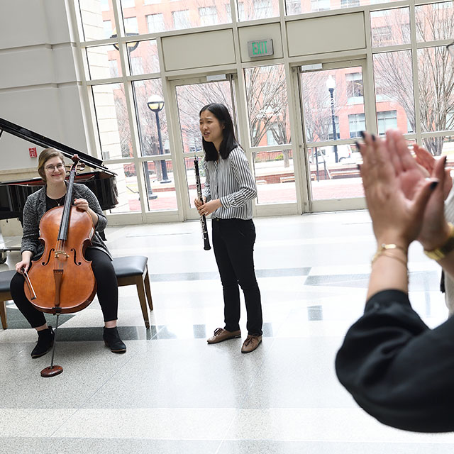 An impromptu audience in the Weinberg Building applaud Peabody Institute students Olivia Rainoff on cello and Sophia Lou, who is playing the oboe. 