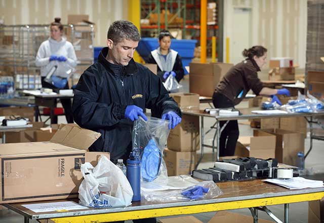 Garet Howard, finance director for the health system supply chain, places face shields and personal protection packs in plastic packaging for delivery to Johns Hopkins hospitals.