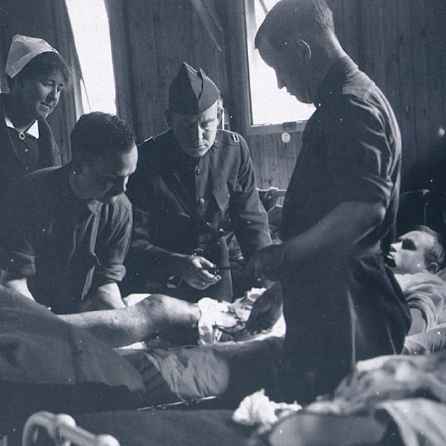 Army Doctors and an army nurse stand around a patient during the 1919 flu.