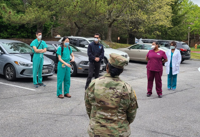 nurses and a soldier talk in a parking lot