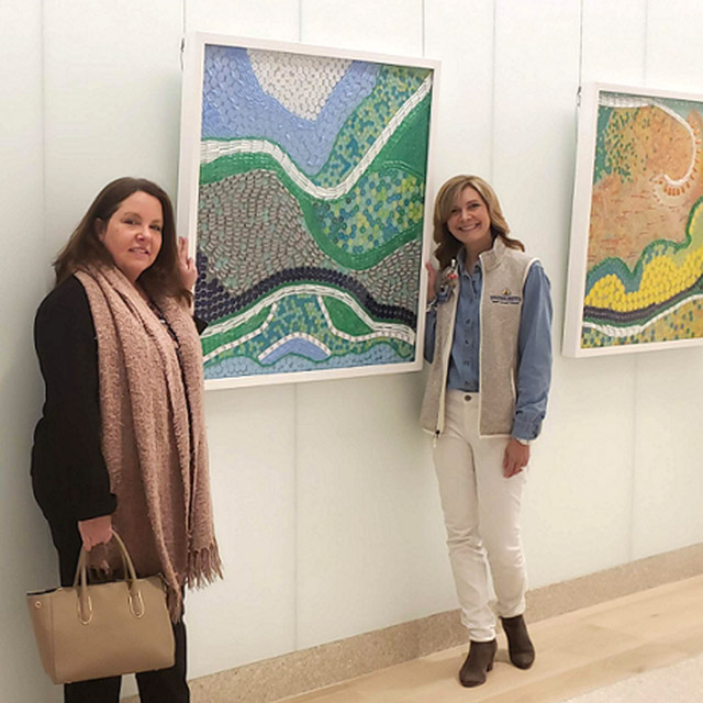 Artist Billie Coursey-Lookingbill, left, and LeighAnn Sidone, Suburban Hospital vice president and chief nursing officer, stand next to the Small Things mosaics at the Feb. 21 dedication ceremony.  