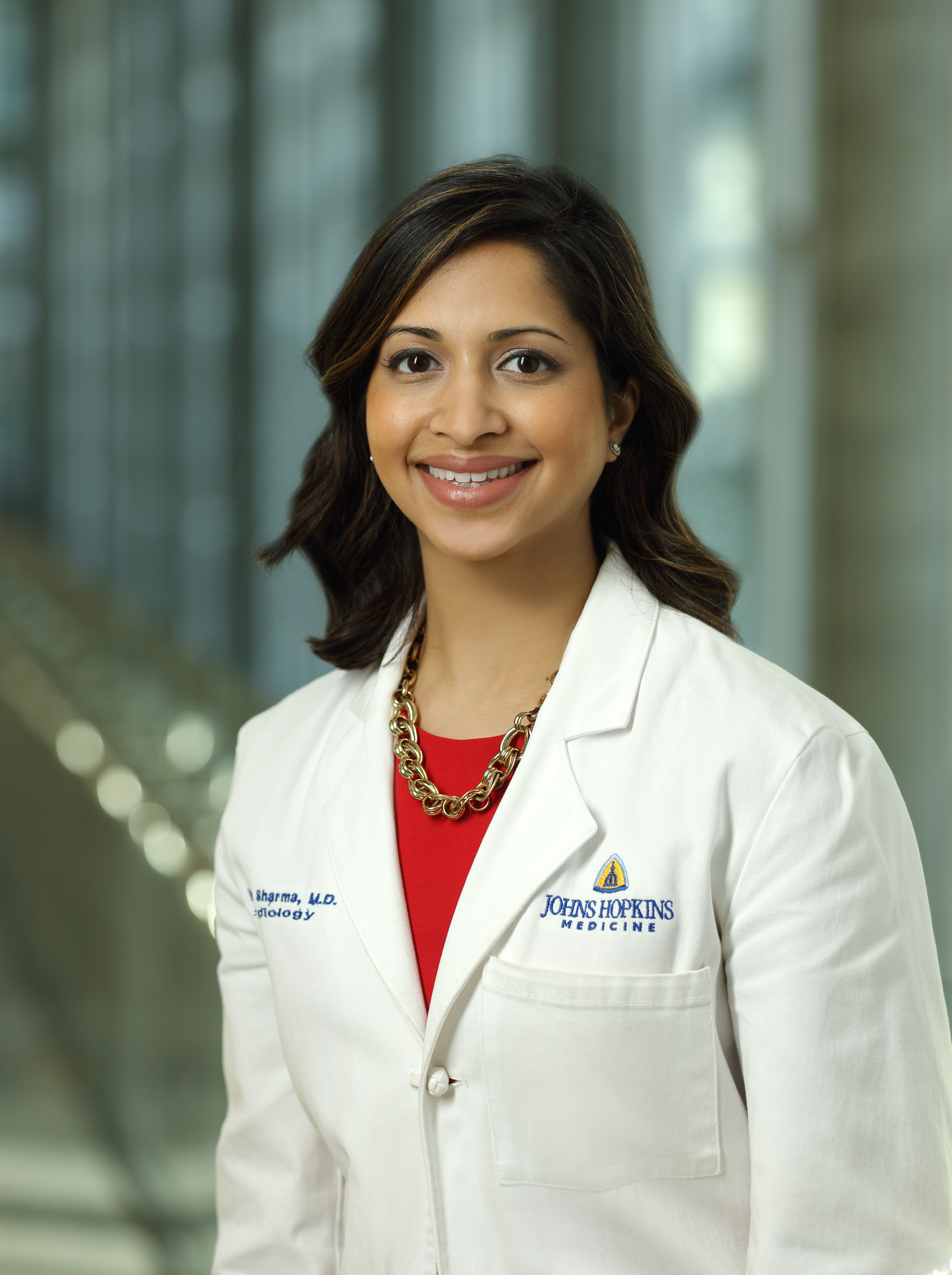 Kavita Sharma, smiling, in formal portrait while wearing medical white coat.