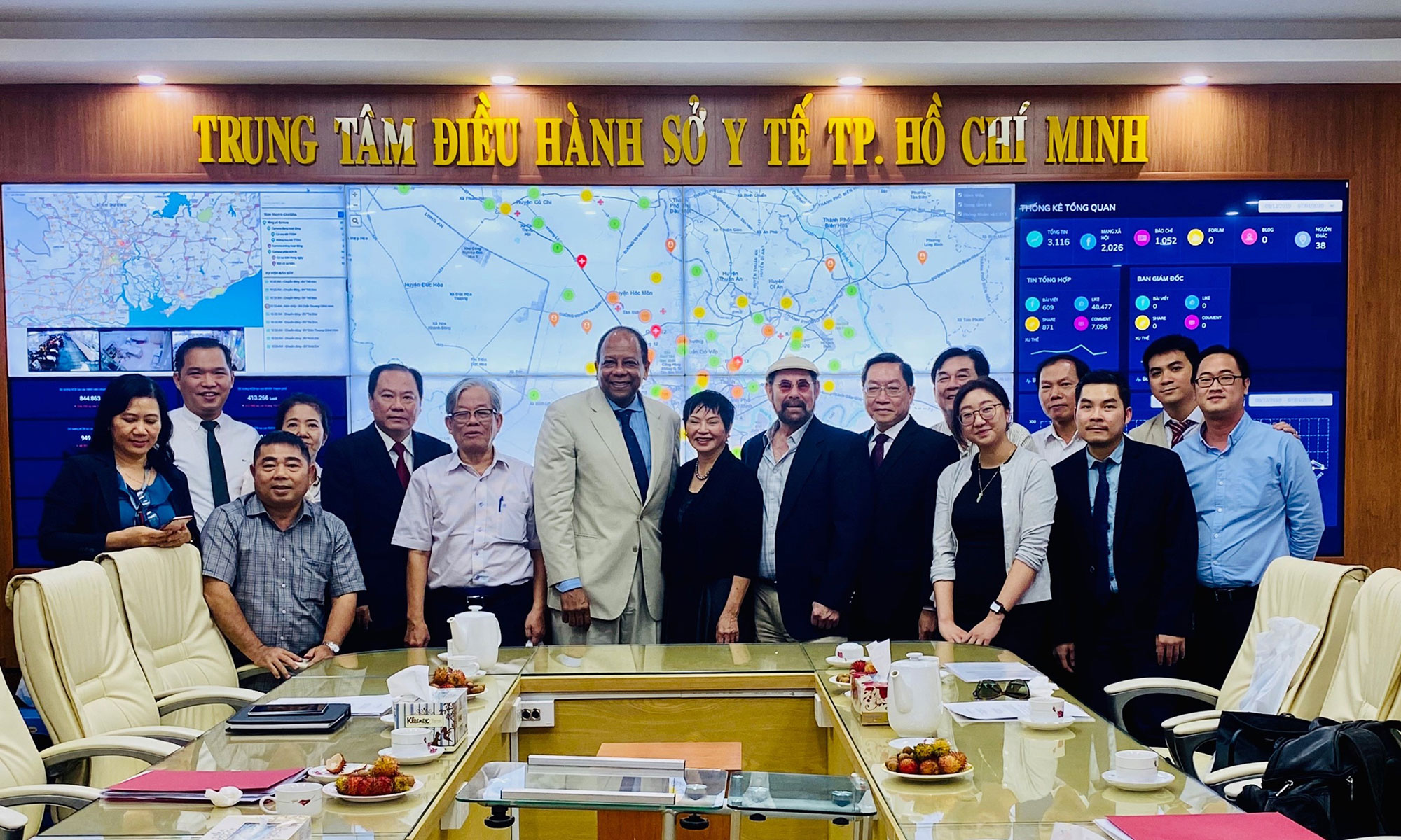 Group of Johns Hopkins physicians and officials from Ho Chi Minh city pose in front of large map of Vietnam.