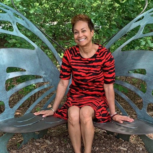 A smiling Jacqueline Beale sitting on a bench
