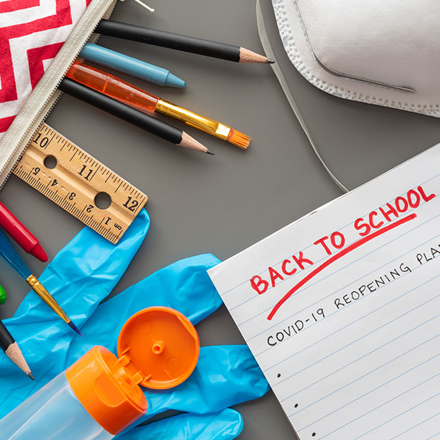 Image shows school supplies, including pencils, a notebook, a mask and hand sanitizer