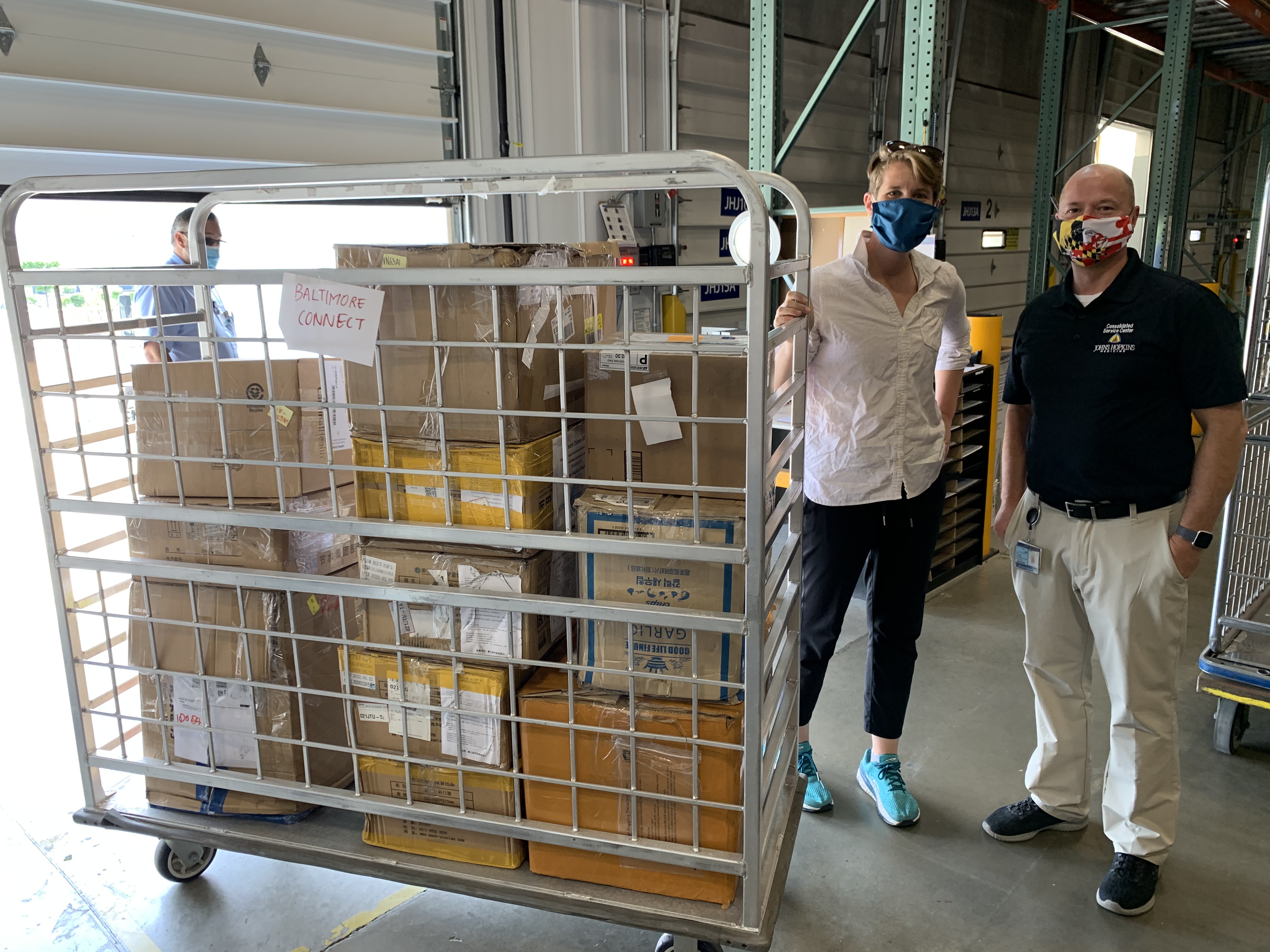 Baltimore CONNECT’s acting executive director Lindsay Hebert accepts face masks from Shawn Durning, Operations Manager for JHHS Consolidated Service Center.