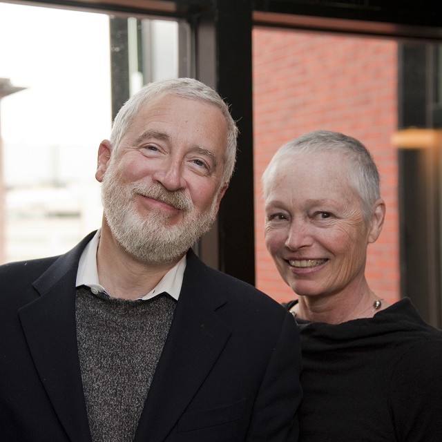 Jason and Beverly Kravitt smile in a portrait of the couple. Both have short gray hair, and Jason has a gray beard.