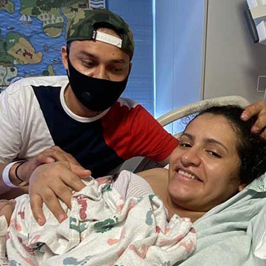 Elsa Lisseth Reyes-Amaya lays in a hospital bed holding her baby, Sofia, with her husband Victor.