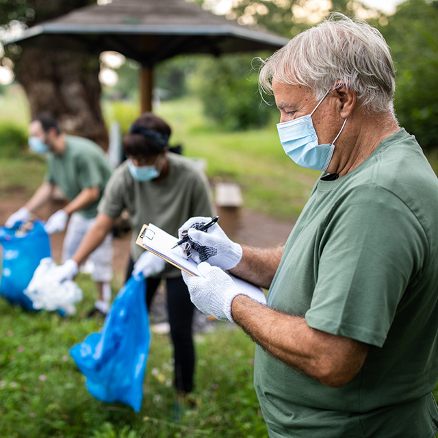 Photo shows a group of volunteers wearing face masks and practicing social distancing during a neighborhood cleanup event.